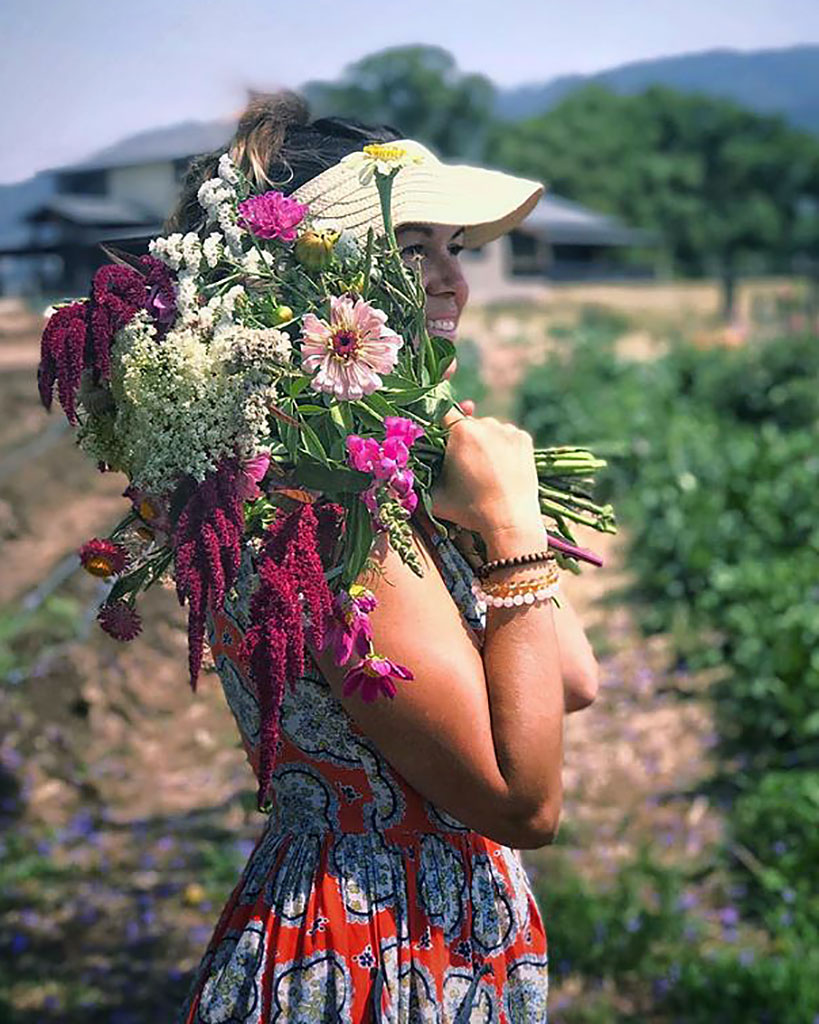 Danielle Holmes with some of the blooms she is growing for the Deities at New Govardhana, thanks to some ingenious watering methods.